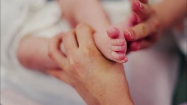 Bebeğin bacaklarına masaj yapan bir ebeveynin ellerini kapat.