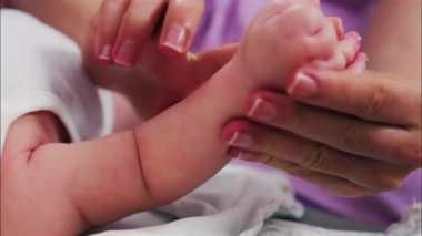 Bebeğin ellerine ve kollarına masaj yapan bir ebeveynin ellerini kapat.