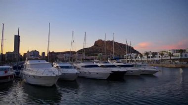 Alicante, İspanya - 22 Mayıs 2025: Günbatımında kaleye bakan Alicante limanına çok sayıda tekne yanaştı
