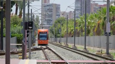 Alicante, İspanya - 26 Mayıs 2025: Turuncu bir tramvay Porta del Mar 'a doğru hafif demiryolu koridoru boyunca süzülüyor
