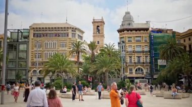 Valencia, Spain - May 28, 2025: Tourists and locals gather in an open square dotted with palms in daylight