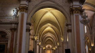 Symmetrical interior view down a Gothic nave with ribbed vaults and ornate columns in the Valencia Cathedral, Spain