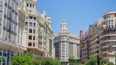 Valencia, Spain - May 29, 2025: Cyclists and pedestrians on a pedestrian boulevard leading toward the landmark towered buildings of Plaza del Ayuntamiento