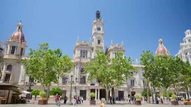 Valencia, Spain - May 29, 2025: Palm framed view of the Valencia City Hall with clock tower under clear skies