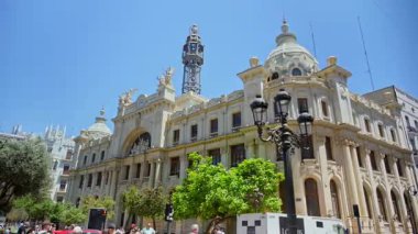 Valencia, Spain - May 29, 2025: Ornate Central Post Office with sculptural details and the metal communications tower behind a decorative lamppost.