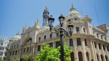 Valencia, Spain - May 29, 2025: Ornate Central Post Office with sculptural details and the metal communications tower behind a decorative lamppost.