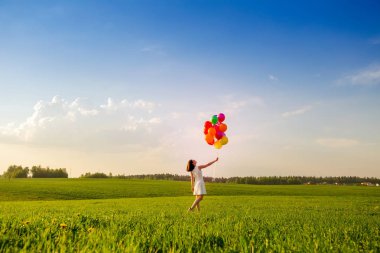İşten sonra açık havada Tema zaman. Renk hava balonları mavi gökyüzü zemin yaz yeşil alana kızla. Güneşli yaz akşam. Özgürlük kavramı.