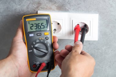 Elektrikçi gerilim yuvasında Sınayıcısı ile kontrol. Profesyonel multimetre el yakın çekim.