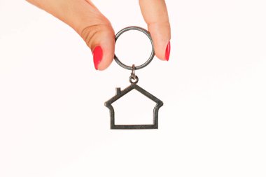 Kadın parmakları ile kırmızı manikür, pembe arka plan izole Anahtarlık ev tutan.