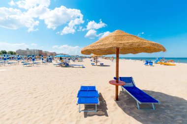 Temiz beyaz kum plaj. Rimini güneşli bir plaj. Şemsiye ve güverte sandalyeleri deniz mavi gökyüzü arka plan üzerinde güneş.