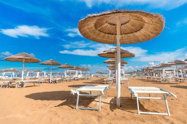 Hasır şemsiyeleri sahilde. Rimini boş plaj şezlong ve şemsiye ile. Açık mavi gökyüzü arka plan. Yaz eğlence. Tatil Tema.