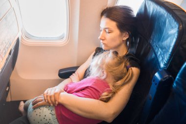 Uçağın içinde uyuyan çocuk ile anne. Rahat uçuş koşulları. Hava ulaşım arka plan.