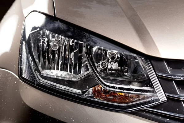 Car headlight. Clean car headlamp with water drops after washing. Exterior of modern car.