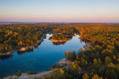 Güzel manzara ile bir göl günbatımı ve orman tarafından sıcak güneş ışığı yaktı. Havadan görünümü. Sıcak sonbahar akşam.