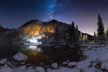 Dağlarda yıldızlı kış gecesi. Derin mavi gece gökyüzünde dağ tepe üzerinde Samanyolu. Kar ve dağ renkli gece manzarası.