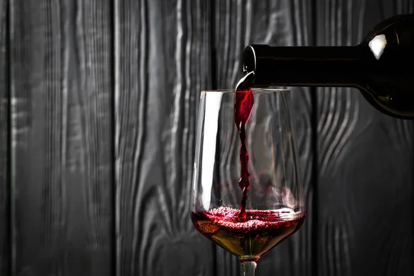 Красное Вино Наливается Бутылки Черном Деревянном Фоне Вкусные Алкогольные Напитки — стоковое фото