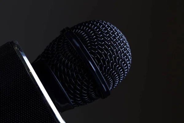 Black microphone head isolated on black background close-up.