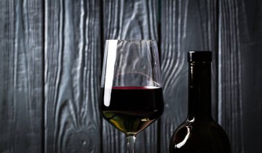 Bardağı ve siyah ahşap zemin üzerine kırmızı şarap şişe şarap. Yakın çekim görünümü. Stüdyo çekimi. Kopya alanı.