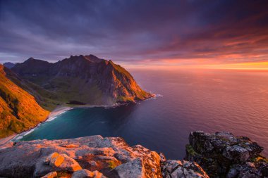Gün batımında Kuzey Norveç kıyı şeridi. Kayalar kırmızı pembe kutup gökyüzü altında. Ryten dağın Lofoten Adaları.