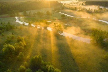 Çayır mevsiminde yaz sisli bir sabah. Sabah güneşi vadiyi nehirle aydınlatıyor. Güneşli manzaralı kırsal arka plan.