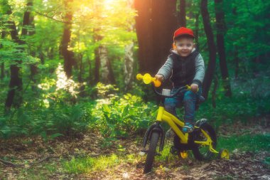 Küçük bebek ormandaki bir bisiklete binmek için öğrenme.