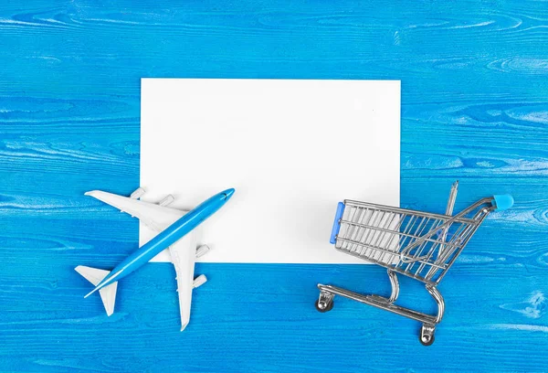 模型的飞机 杂货车和空白纸上的蓝色木质背景 旅游理念 门票购买 — 图库照片