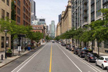 Montreal, Kanada - 4 Temmuz 2025: Kentsel sokak, binalar ve Quebec 'te park edilmiş arabalarla şehir merkezi manzarası