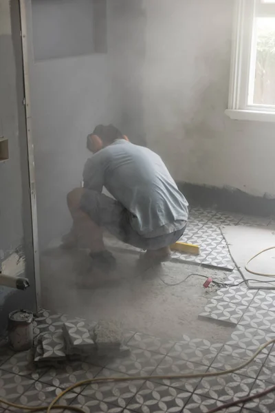 Grinding the concrete floor to complete tiling in a bathroom dusty environment