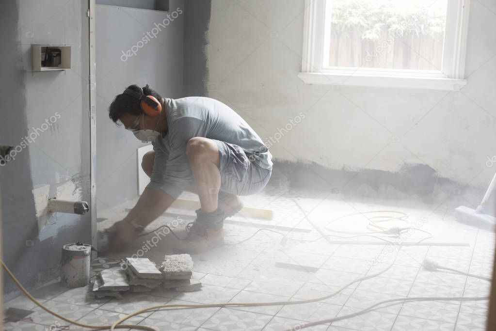 The grinder moves continually across the concrete floor to level the floor for tiling in a bathroom during home renovation