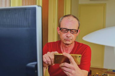 Orta masa başında oturan gözlüklü adam yaşlı. Cep telefonu kullaranarak olgun adam. Üst düzey kavramı. Evde office dostum