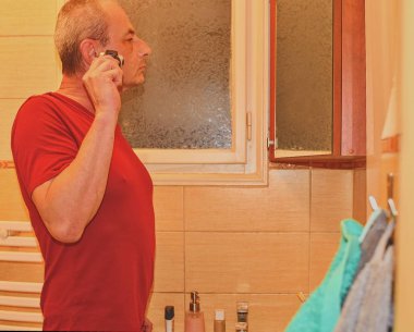 Orta bir banyoda tıraş, tıraş kullanarak adam yaşlı. Olgun adam evde. Üst düzey kavramı. 