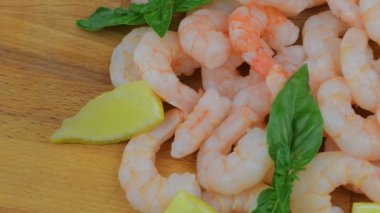 Limon dilimleri ve Doğrama Kurulu üzerinde fesleğen yaprakları ile pişmiş ve soyulmuş karides. Gıda video. Sağlıklı gıda. Biyo tarifi