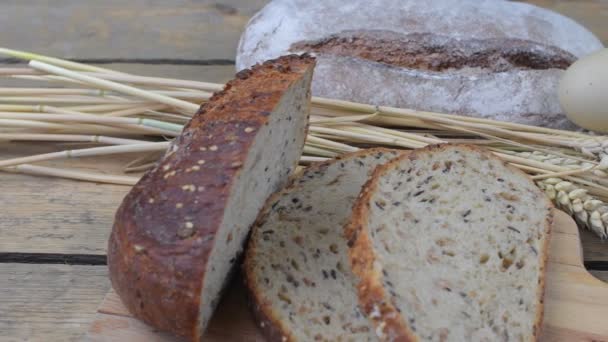 Loafs brood, sneetjes brood, meel, eieren en oren van graan op hout achtergrond. Rustiek en landelijk concept. Close-up. Plat leggen — Stockvideo