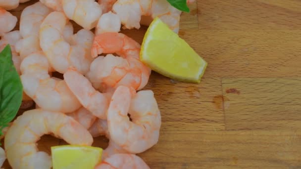 Vařené a oloupané krevety s plátky citronu a lístky bazalky na prkénko. Potravin video. Zdravé jídlo. Bio recept