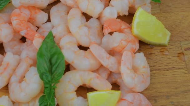 Crevettes cuites et pelées avec tranches de citron et feuilles de basilic sur la planche à découper. Vidéo sur la nourriture. Une nourriture saine. Recette bio — Video