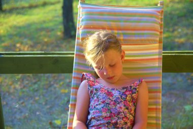 Küçük kız bahçede bir güneş banyosu yapıyor. Rüya gibi ve romantik bir görüntü. Yaz ve mutlu çocukluk konsepti