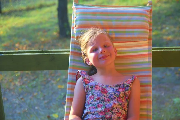 La bambina si sta prendendo un bagno di sole in giardino. Immagine sognante e romantica. Estate e felice concetto di infanzia — Foto Stock