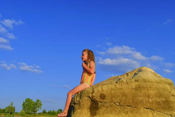 Porträt eines kleinen blonden Mädchens, das im Badeanzug auf Felsen im See posiert. Sommer und glückliche Kindheit. Kopierraum in strahlend blauem Himmel — Stockfoto
