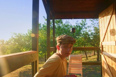 Genç çocuk bir veranda üzerinde oturan ve taze elma yeme. Rüya gibi ve romantik görüntü. Yaz ve mutlu çocukluk kavramı