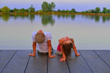 Küçük kız ve erkek düz kapak ile iskelede oturuyor. Erkek ve kız yukarı doğru gökyüzü üzerinde arıyoruz. Sevgi, dostluk ve çocukluk kavramı. Güzel romantik günbatımı resim