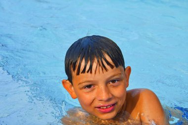 Sevimli küçük çocuk genel yüzme havuzunda. Yüzme havuzunda küçük şirin çocuk portresi. Güneşli yaz günü. Yaz ve mutlu çocukluk kavramı. 