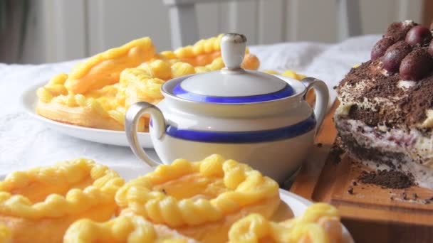 Schokoladenkuchen mit Kirschen, geriebener Schokolade und Schlagsahne. hausgemachte Windbeutel auf festlichem Tisch. Zuckerdose vorhanden. Nahaufnahme. Hintergrund Küche — Stockvideo