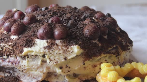 Pastel de chocolate con cerezas, chocolate rallado y crema batida. Bollos de crema caseros en la mesa festiva. Azucarero vintage. Primer plano. Fondo de cocina. Baja DOF — Vídeos de Stock