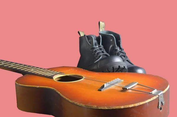 Concept de rock and roll. Bottes noires et guitare acoustique. Bottes Rock and roll sur fond rose — Photo