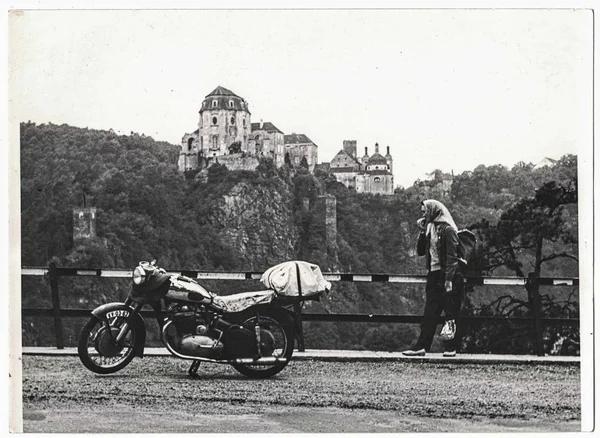 Retro photo shows female motorcyclist on summer trip. Castle on background. — Stock Photo, Image