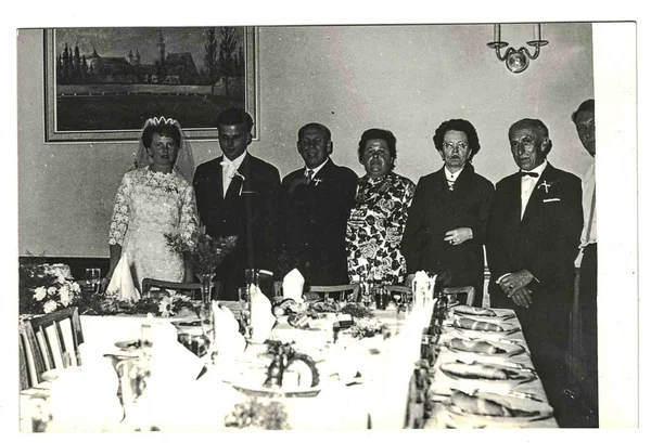 Photo vintage montre les jeunes mariés et les invités de mariage posant à la table de mariage. Photographie noir et blanc rétro . — Photo
