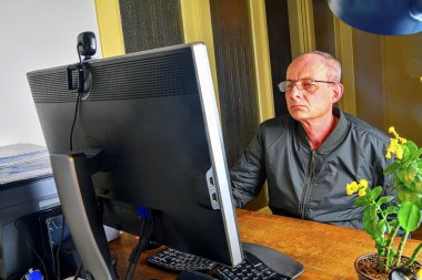 Orta masa başında oturan gözlüklü adam yaşlı. Kişisel bilgisayar kullanan olgun adam. Üst düzey kavramı. Ofiste çalışan adam. 