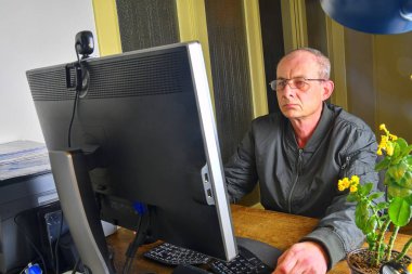 Orta masa başında oturan gözlüklü adam yaşlı. Kişisel bilgisayar kullanan olgun adam. Üst düzey kavramı.