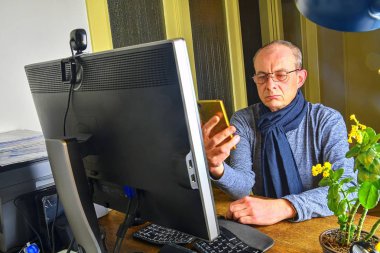 Orta masa başında oturan gözlüklü adam yaşlı. Cep telefonu kullaranarak olgun adam. Üst düzey kavramı. Evde office dostum.