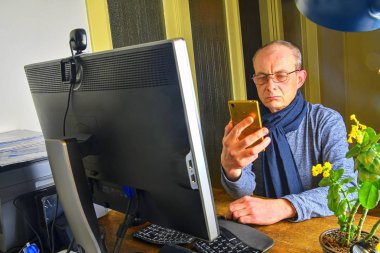 Orta masa başında oturan gözlüklü adam yaşlı. Cep telefonu kullaranarak olgun adam. Üst düzey kavramı. Evde office dostum. 